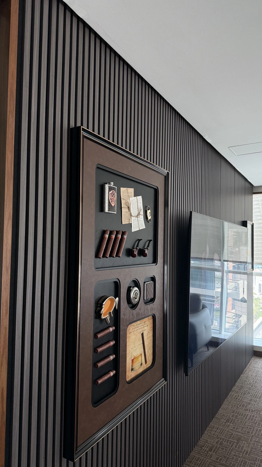 Dark vertical wall panels, framed artwork and a screen inside the office